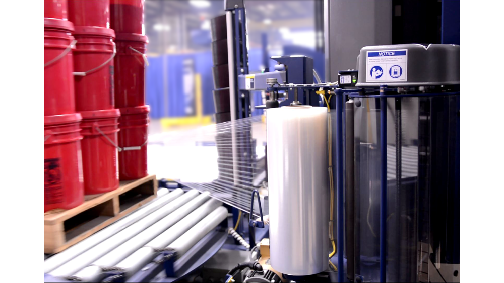 Film Delivery System up close as Red Pails are Stretch Wrapped